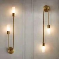 Vano dual-light gold sconces on white panelled wall