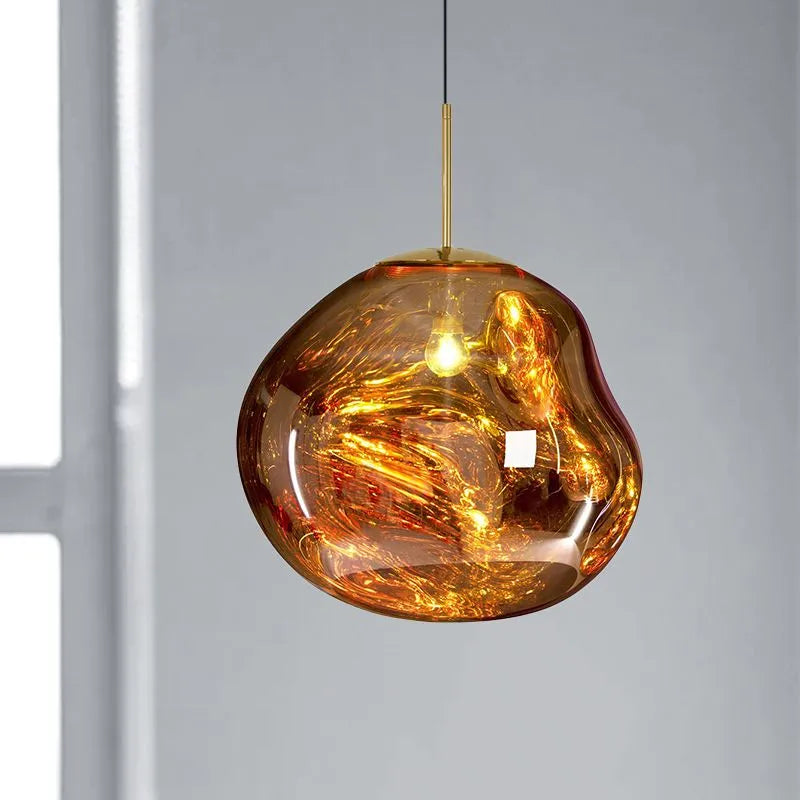 Close view of the Milto gold pendant lit beside a pale wall, showing the uneven rim and mirrored surface