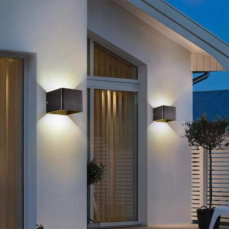 Pair of Nexo black outdoor wall lights on a white house facade in the evening