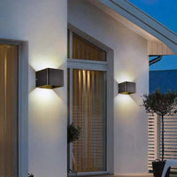 Pair of Nexo black outdoor wall lights on a white house facade in the evening