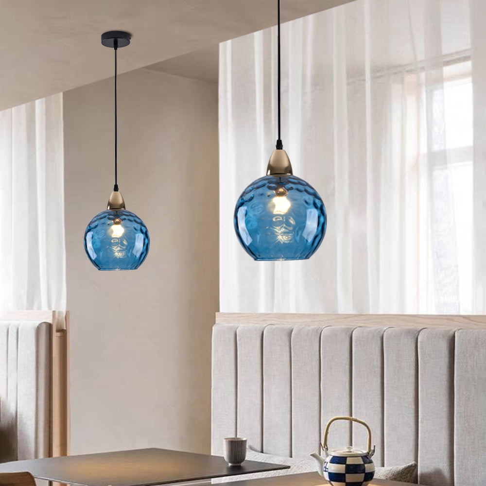 Two Riplo blue glass pendants hanging at different heights over a dining table