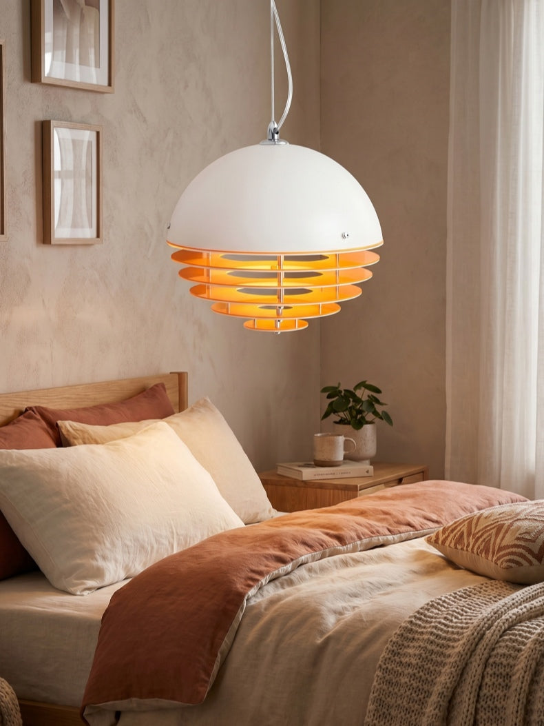 Suno sunset pendant light hanging beside a bed in a plaster walled bedroom