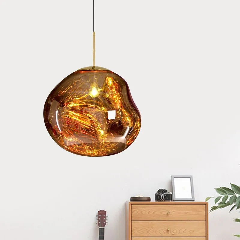 Milto gold pendant light hanging in a bright room above a wooden chest of drawers and a house plant