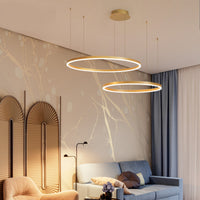 Remo Twin-Ring Pendant Light lit above a living room, gold rings glowing against a pale marbled wall