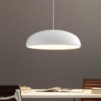 Liro white dome pendant light hanging above a desk against a warm grey wall