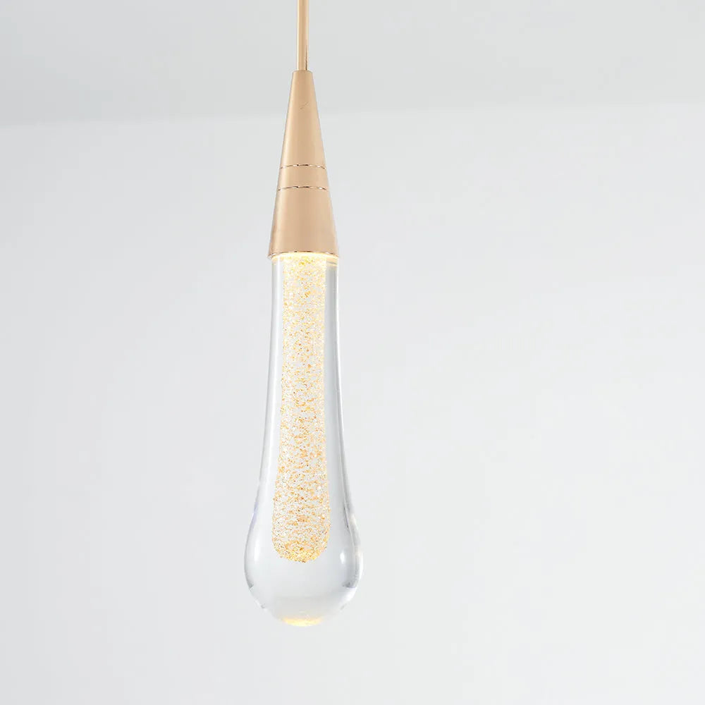 Close view of the Golvara Teardrop Pendant Light showing the ribbed gold cone and glowing crystal drop