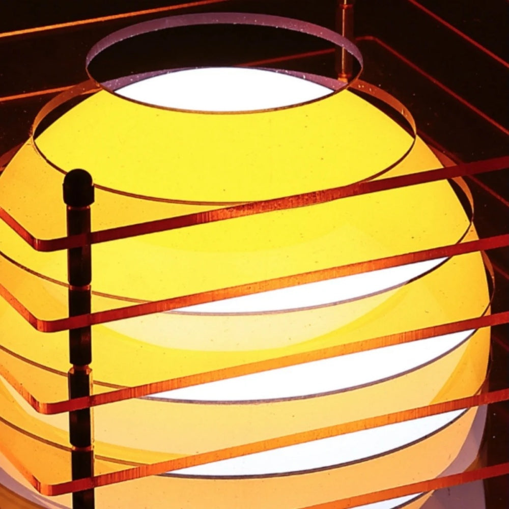 Close up of the Luno table lamp showing the layered white glass sphere behind orange acrylic slats