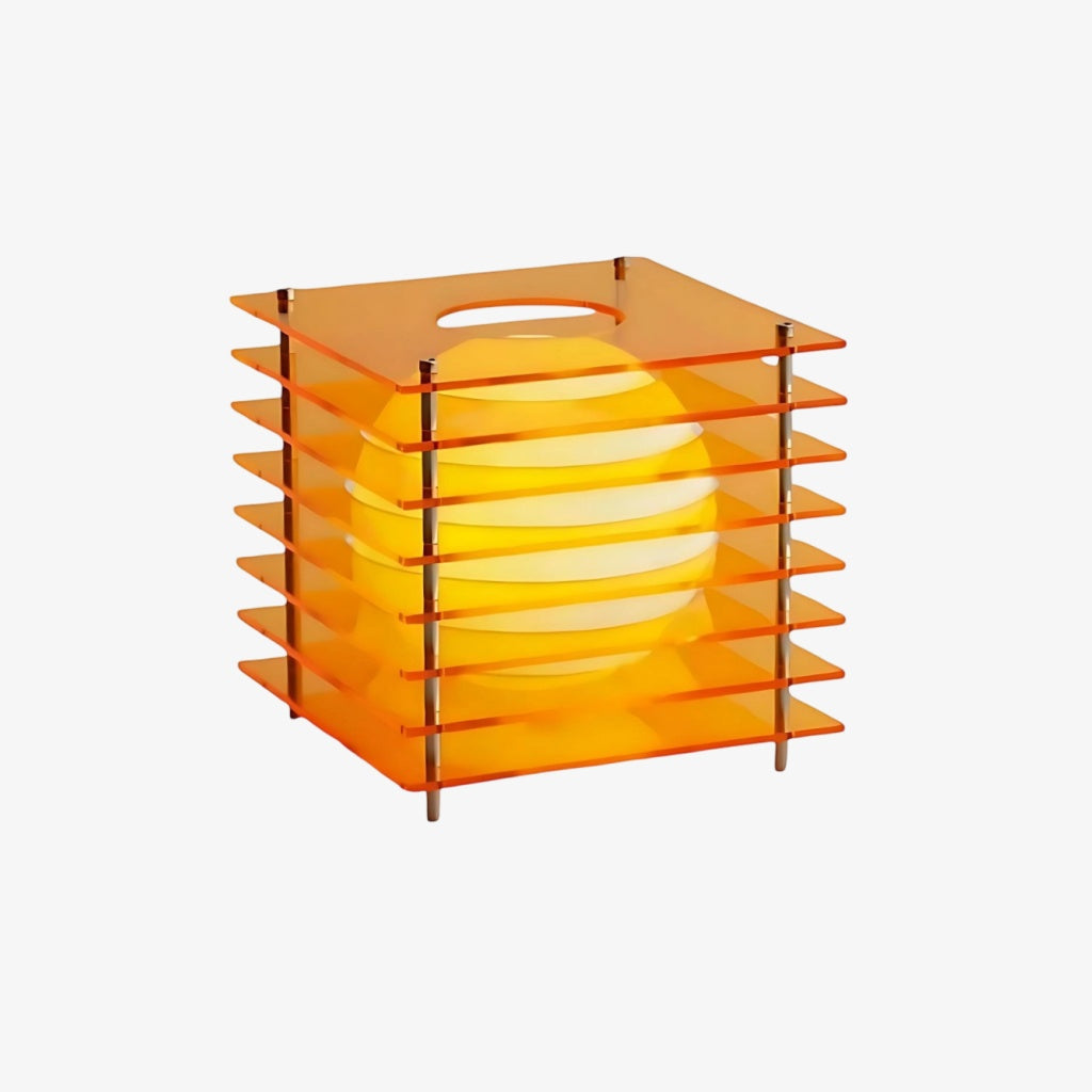 Luno orange acrylic table lamp switched on, the inner globe glowing warm amber behind the layered sheets