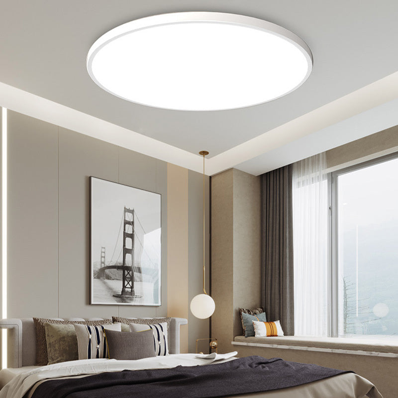 Yano white flush mount ceiling light lit in a neutral bedroom with a window seat