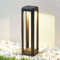Ryda bollard light lit warm white in a bed of white pebbles beside a rendered garden wall