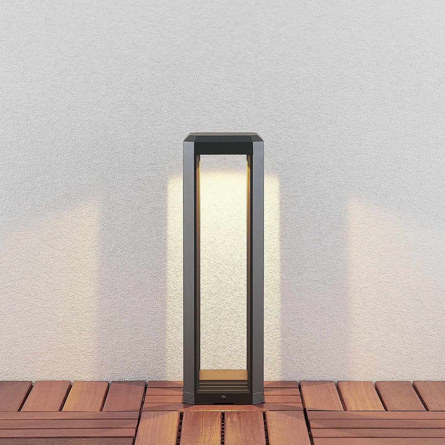 Ryda 50 cm bollard light on timber decking casting a warm downward glow onto a pale wall