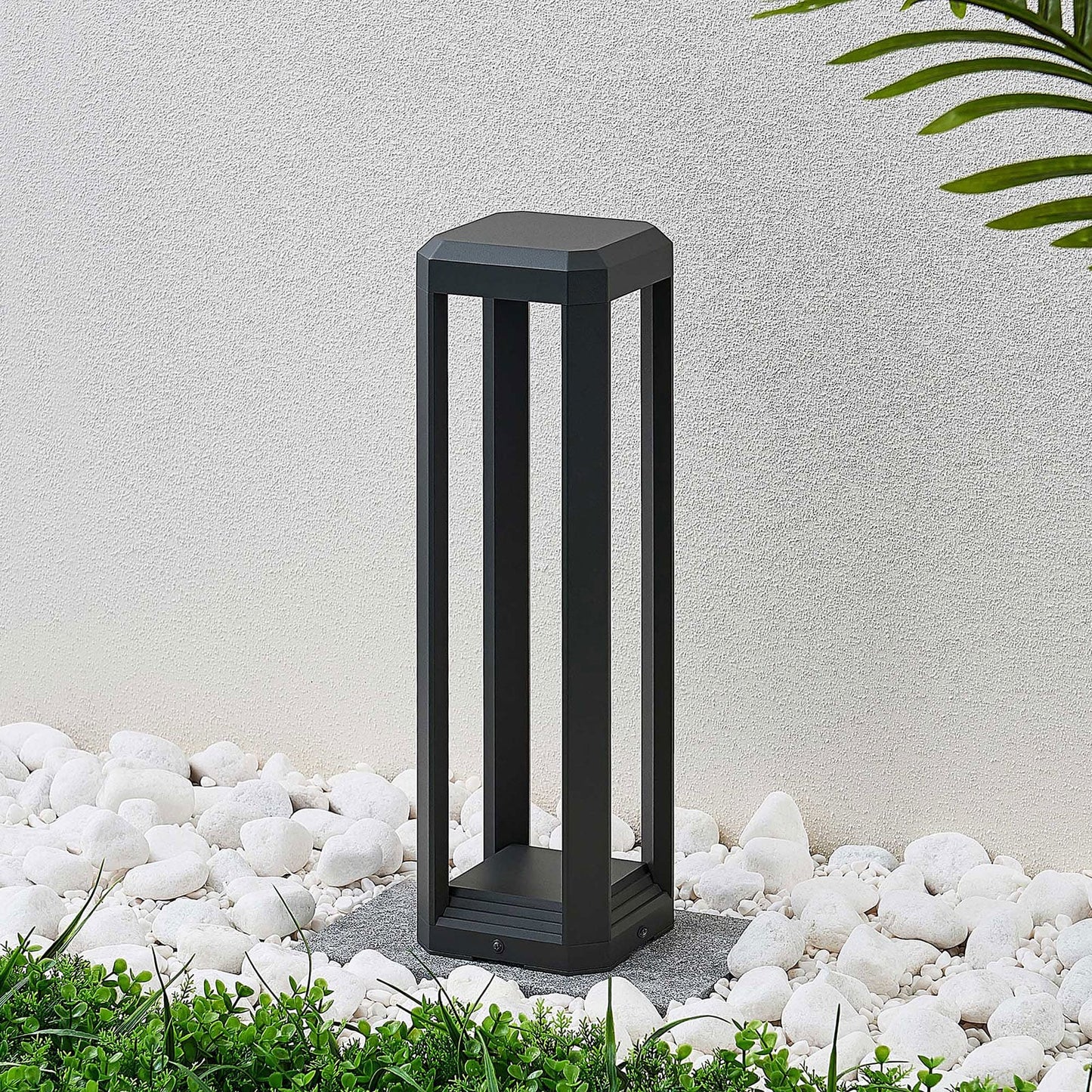 Ryda bollard light switched off, showing the slim anthracite open frame in a garden pebble bed