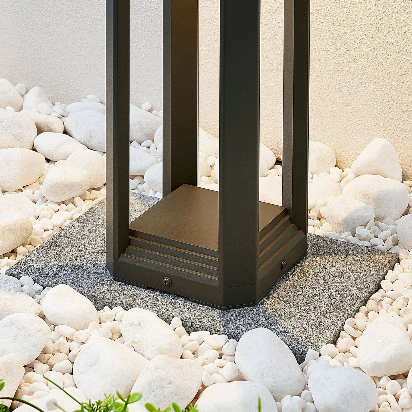 Close view of the Ryda stepped base plinth set on a paving slab among white pebbles