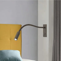 Vexo bronze reading wall light mounted beside a bed with a yellow headboard