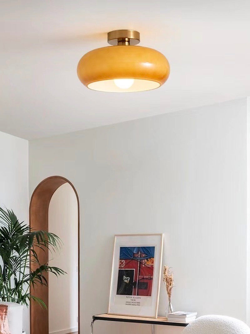 Brass and amber glass ceiling light in a bright hallway with an arched doorway