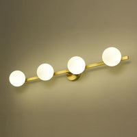 Angled view of the Sevra brass bar with four opal glass globes lit against a warm wall