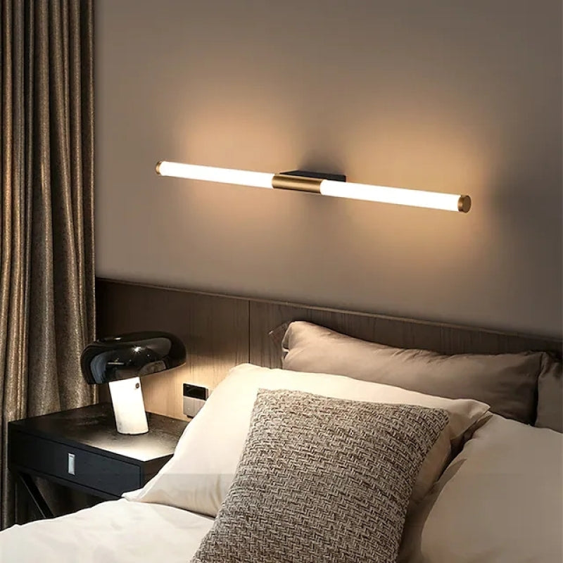 Morva linear wall light mounted horizontally above a bed and lit warm white
