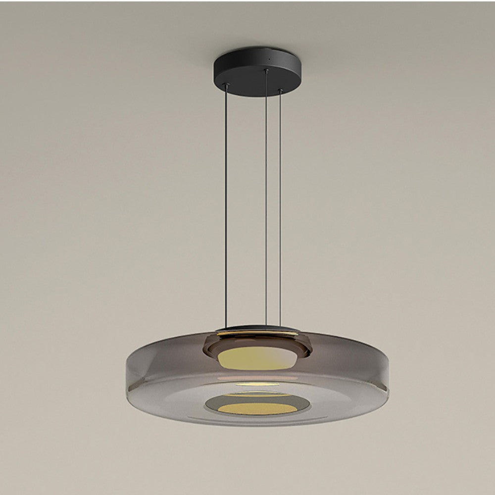 Jovo pendant light lit warm white, showing the metal collar at the centre of the smoke grey glass disc