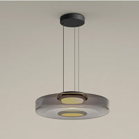 Jovo pendant light lit warm white, showing the metal collar at the centre of the smoke grey glass disc