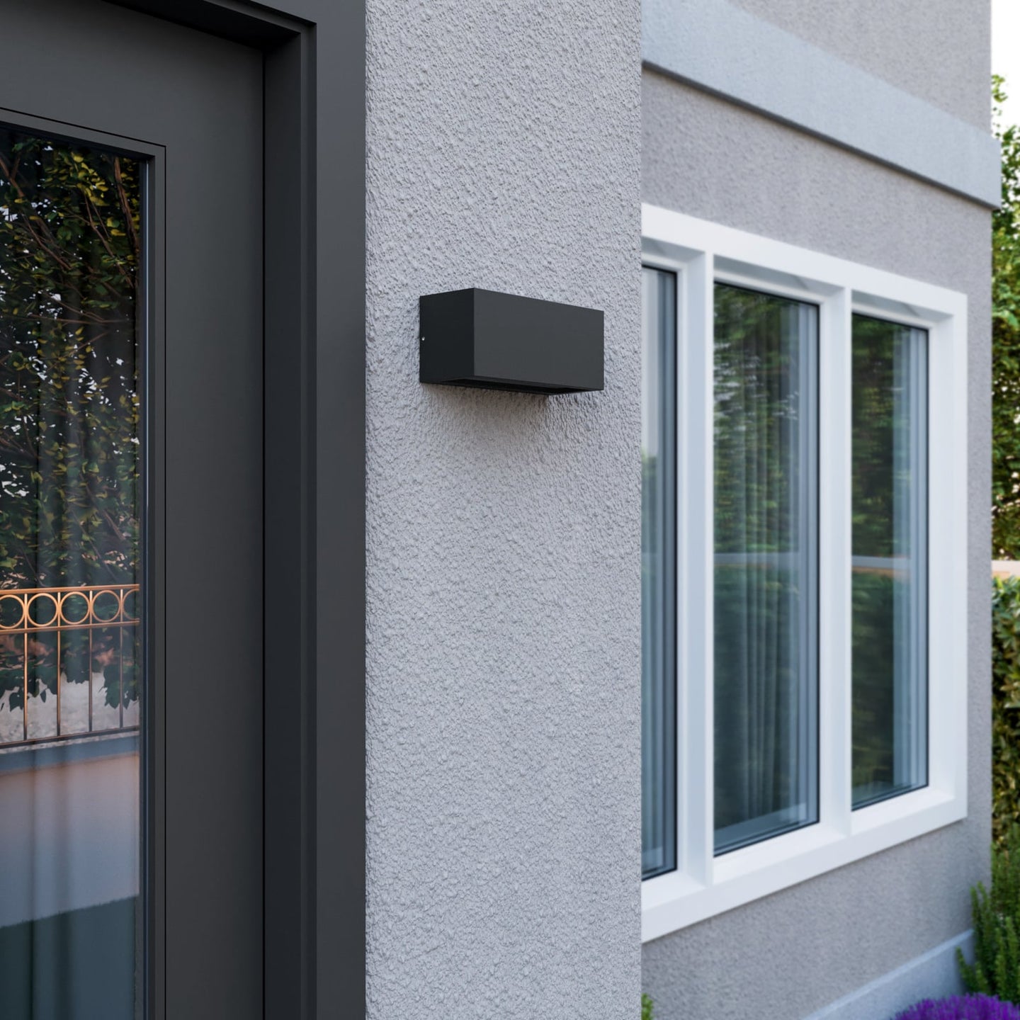 Bexa outdoor wall light mounted in daylight beside a front door, showing the flat anthracite housing against pale render