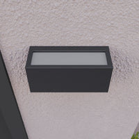 Bexa outdoor wall light viewed from below on a render wall, showing the full width of the frosted diffuser panel