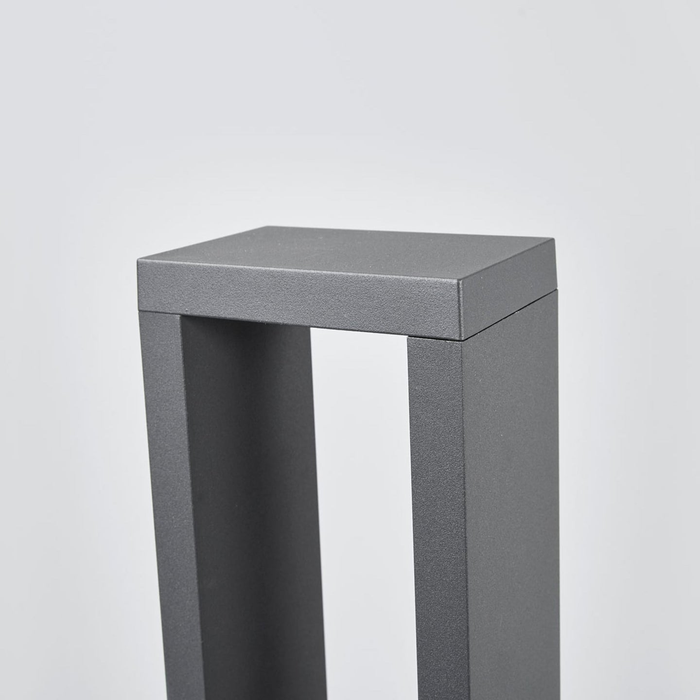 Detail of the anthracite powder-coated top corner of the Jupo path post light showing the textured metal finish