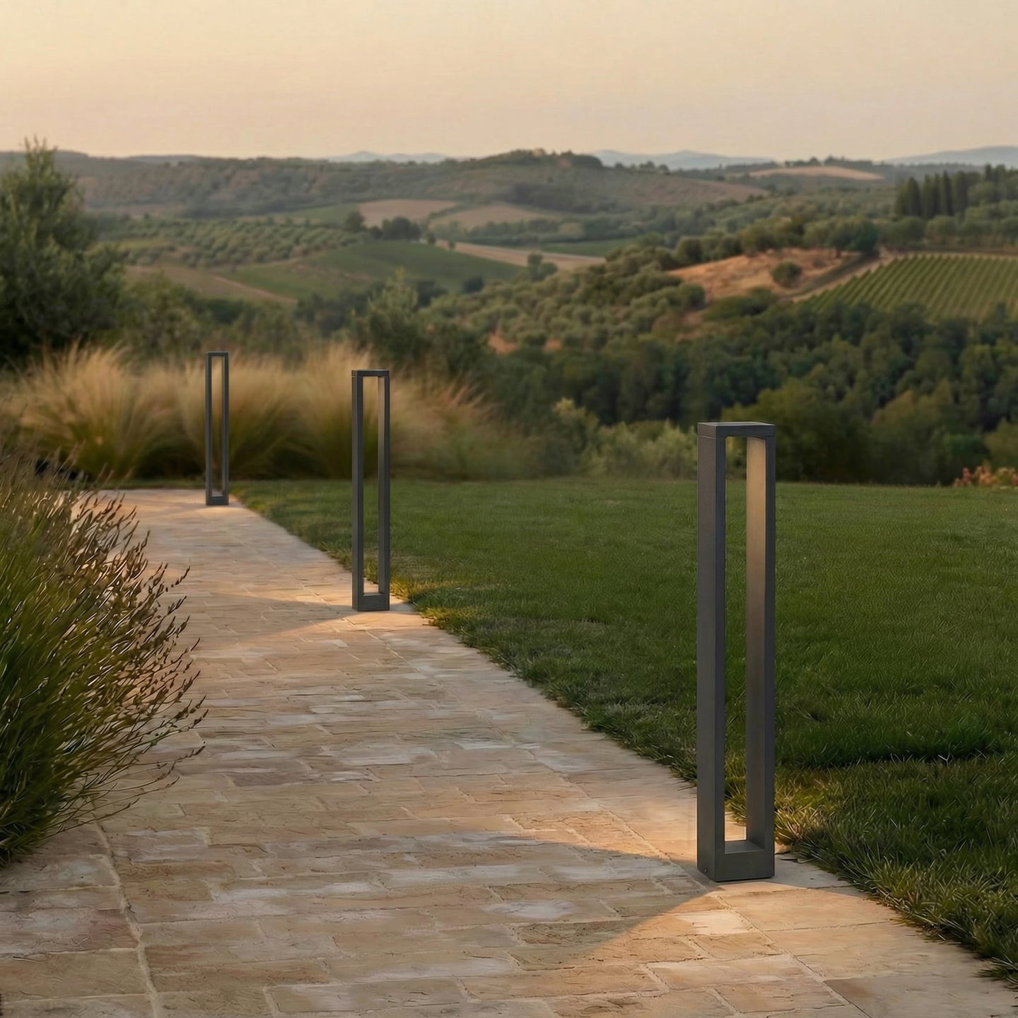 Three Jupo path post lights lining a stone garden path at dusk, each casting a pool of warm light on the paving