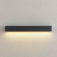 Close view of the Lino Column outdoor wall light lit against a textured render wall, showing the even downward wash of warm light