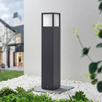 Dewa path post light installed in a garden at dusk beside white pebbles and planting