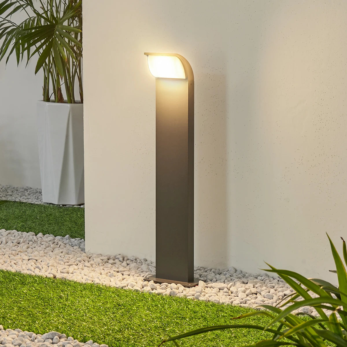 Tilo path light lit at dusk beside a gravel border and lawn