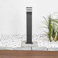 Wider garden view of the Timo anthracite path post light set into a gravel border beside a paved edge
