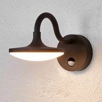 Finno sensor wall light lit on a textured render wall showing the downward wash of light