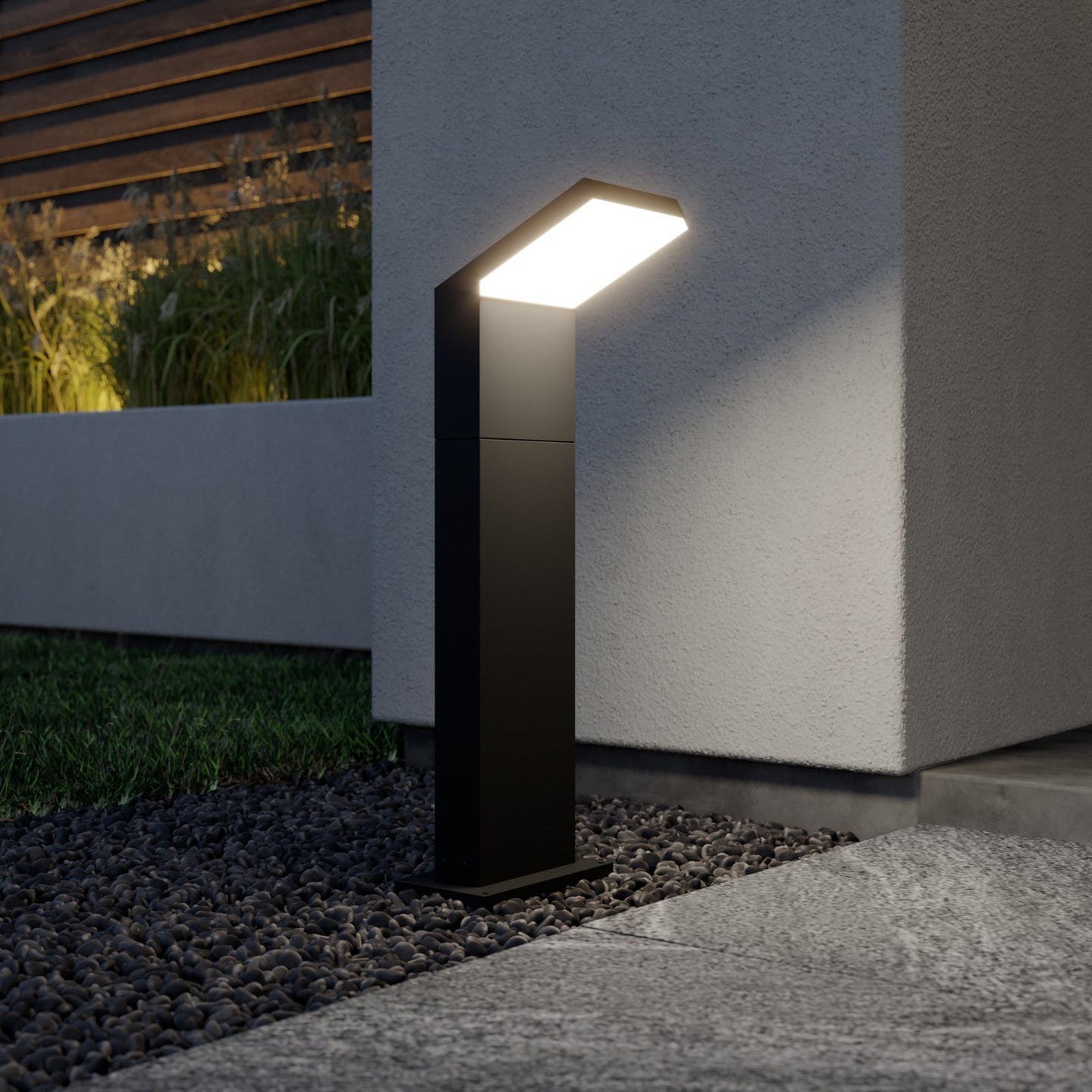 Yola Path Post Light lit at dusk beside a rendered garden wall and gravel bed