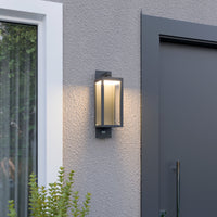 Denro outdoor wall light glowing warm white next to a house entrance and window