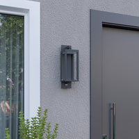 Denro wall light switched off, showing the dark grey aluminium frame against a light render wall