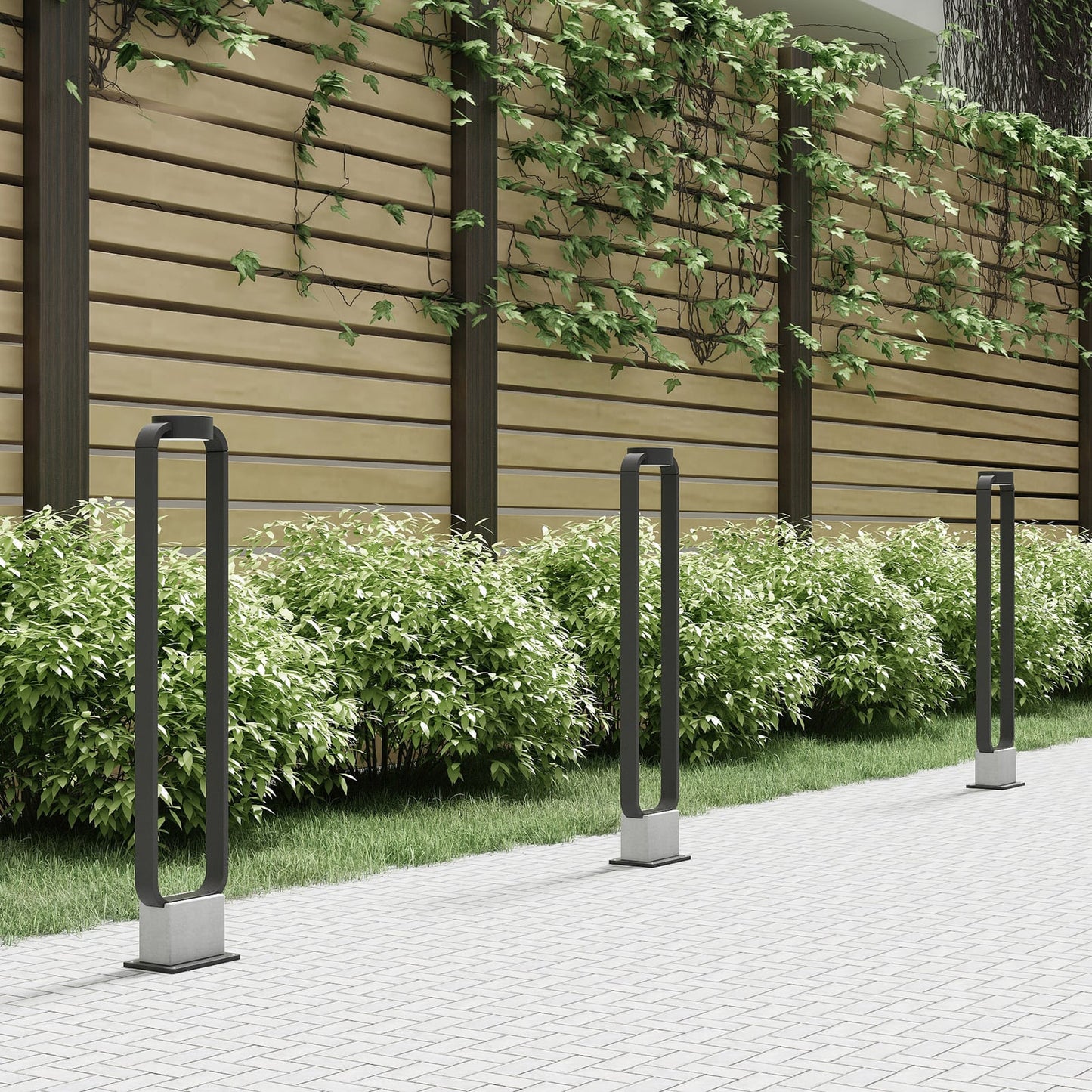 Three Talo concrete bollard lights unlit in daylight along a paved path