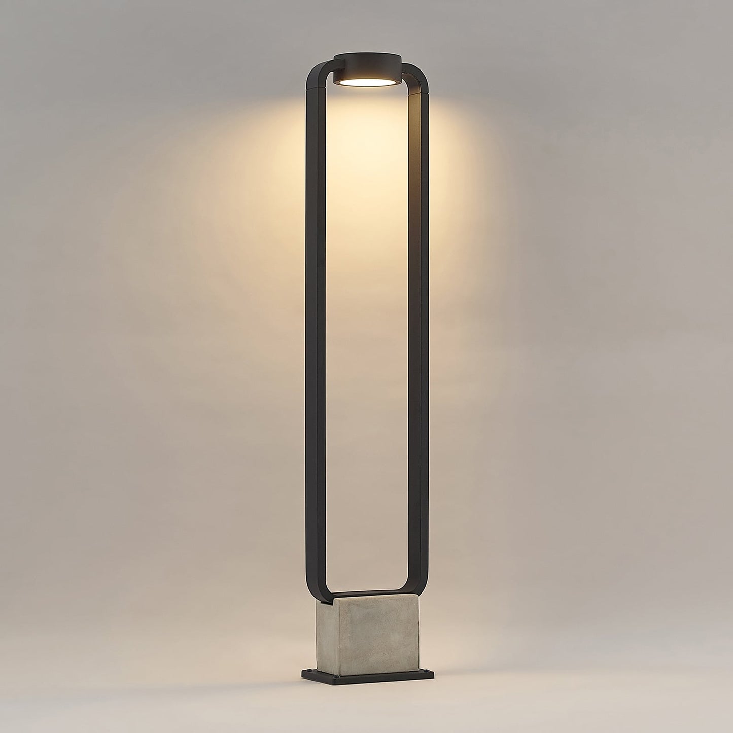 Talo bollard light lit against a plain wall showing the downward warm white beam
