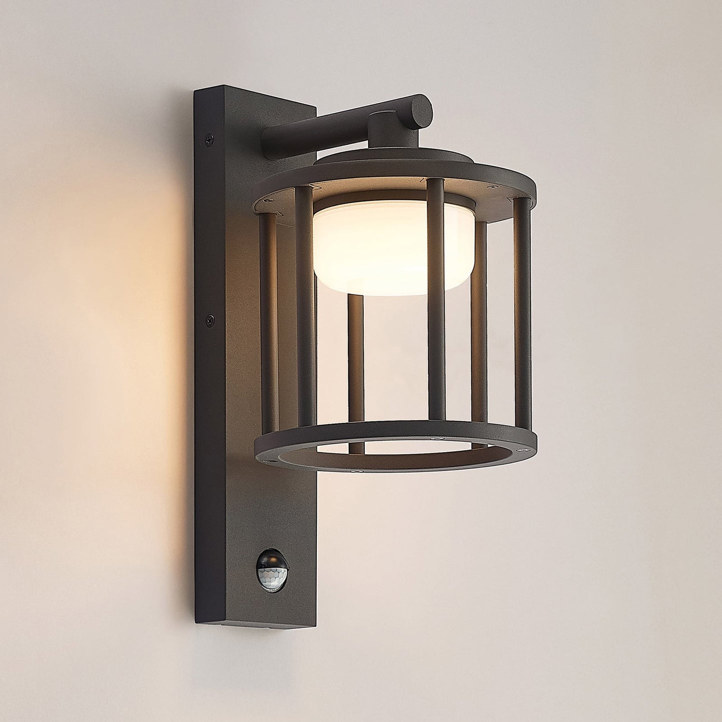 Berno outdoor wall light switched on against a plain warm grey wall showing the downward glow