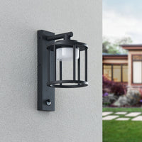 Berno anthracite cage wall light unlit on a grey rendered wall with the motion sensor visible on the bracket