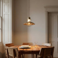 Lusa cage pendant light lit above a round wooden dining table