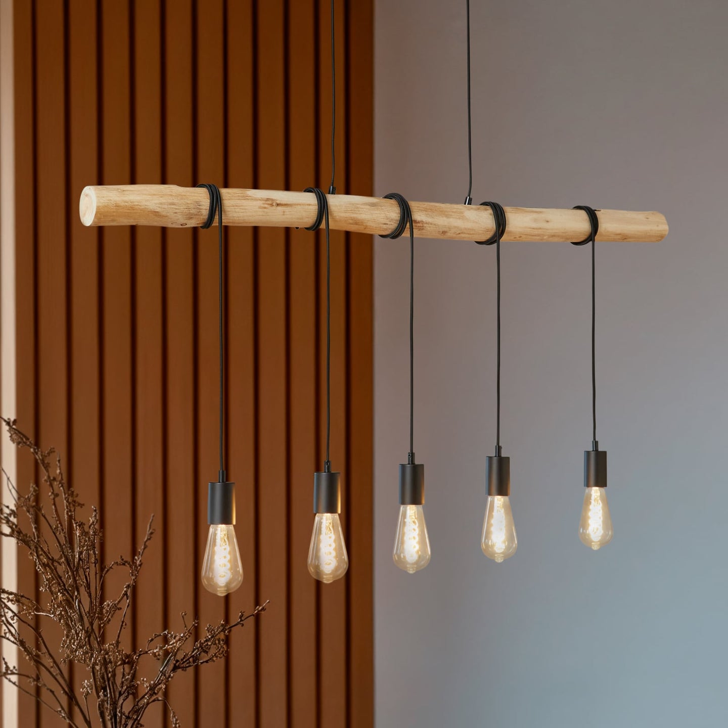 Rovo pendant light seen at an angle against a slatted wood wall, five amber filament bulbs glowing