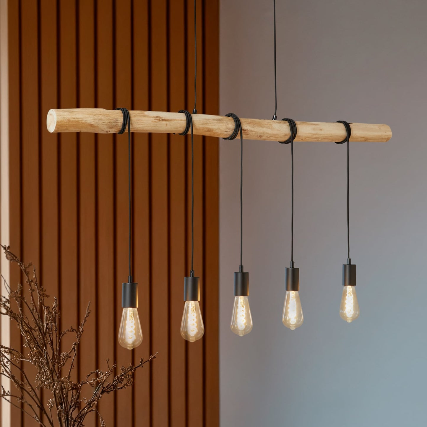 Rovo pendant light seen at an angle against a slatted wood wall, five amber filament bulbs glowing
