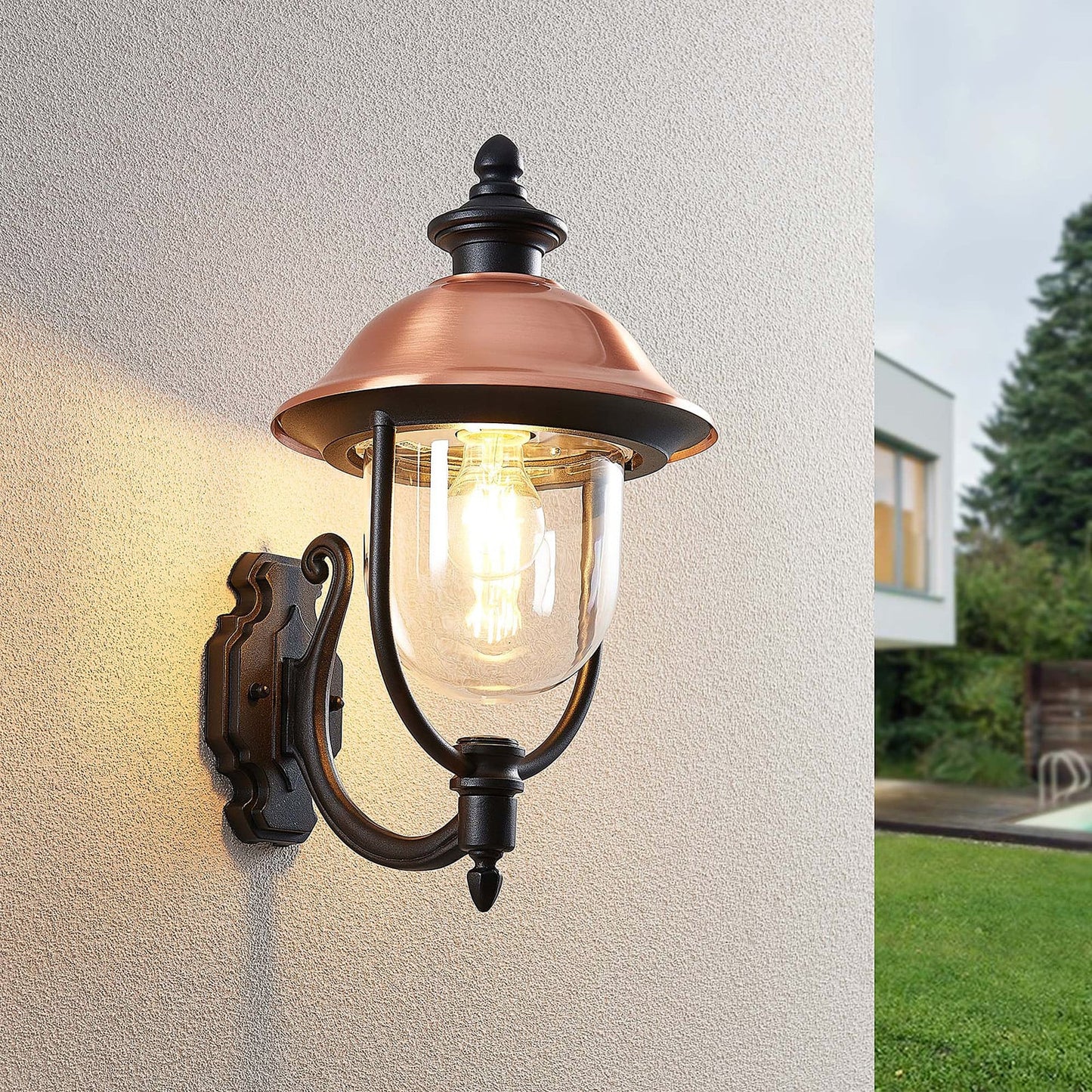 Koma copper outdoor lantern mounted beside a garden with lawn and modern house behind