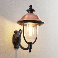 Koma copper wall lantern lit against a pale rendered exterior wall