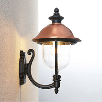 Koma copper lantern lit on an exterior wall corner showing the warm downward wash