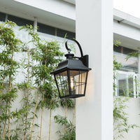 Merto black lantern outdoor wall light mounted on a white pillar next to a garden window
