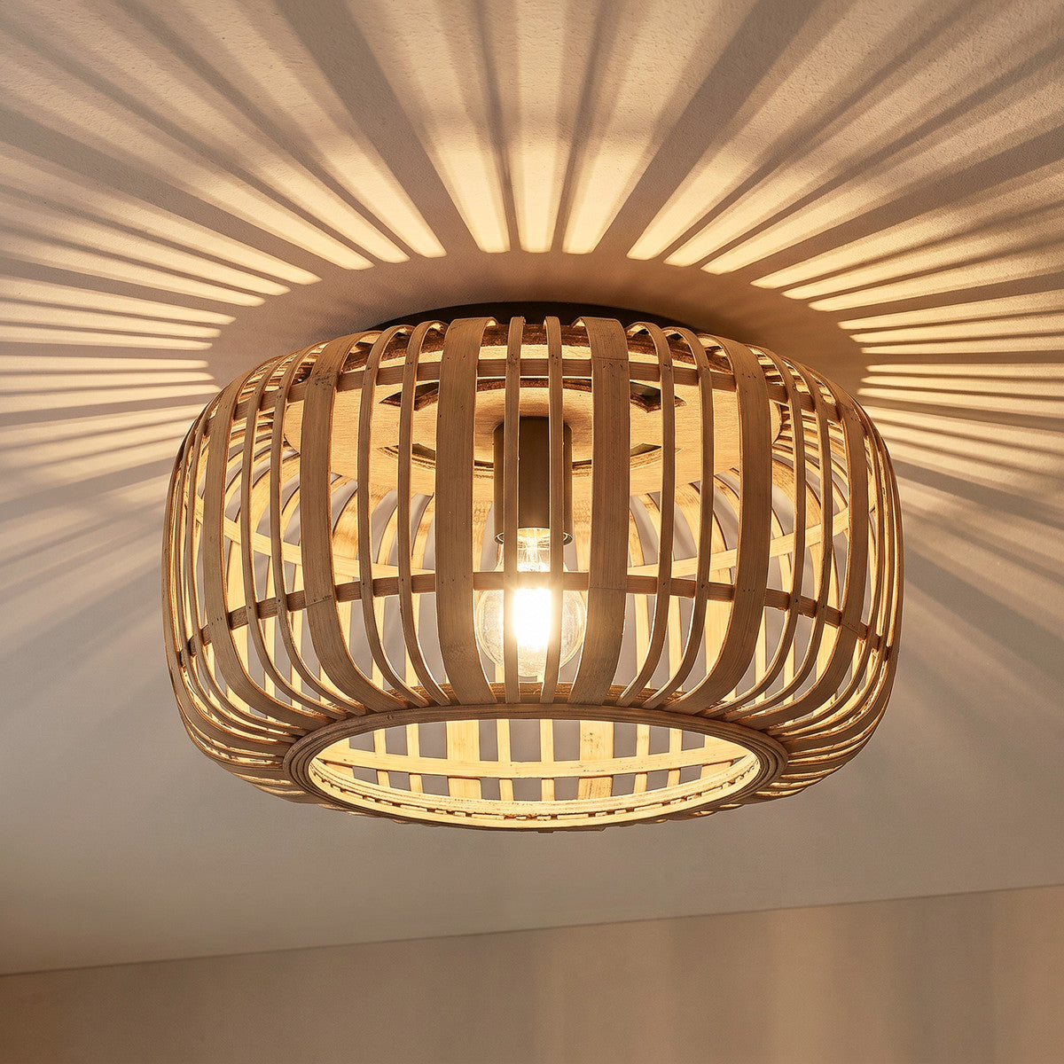 Cana rattan ceiling light lit, casting striped shadows across the ceiling