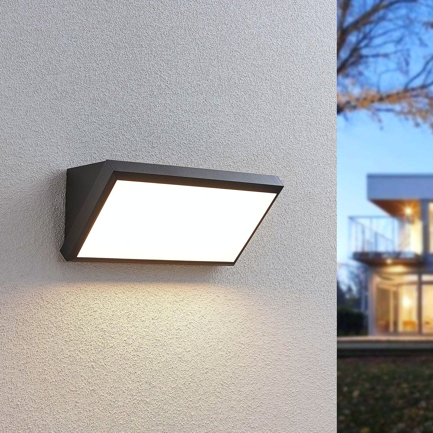 Abbo LED wall light switched on at dusk beside a modern house exterior