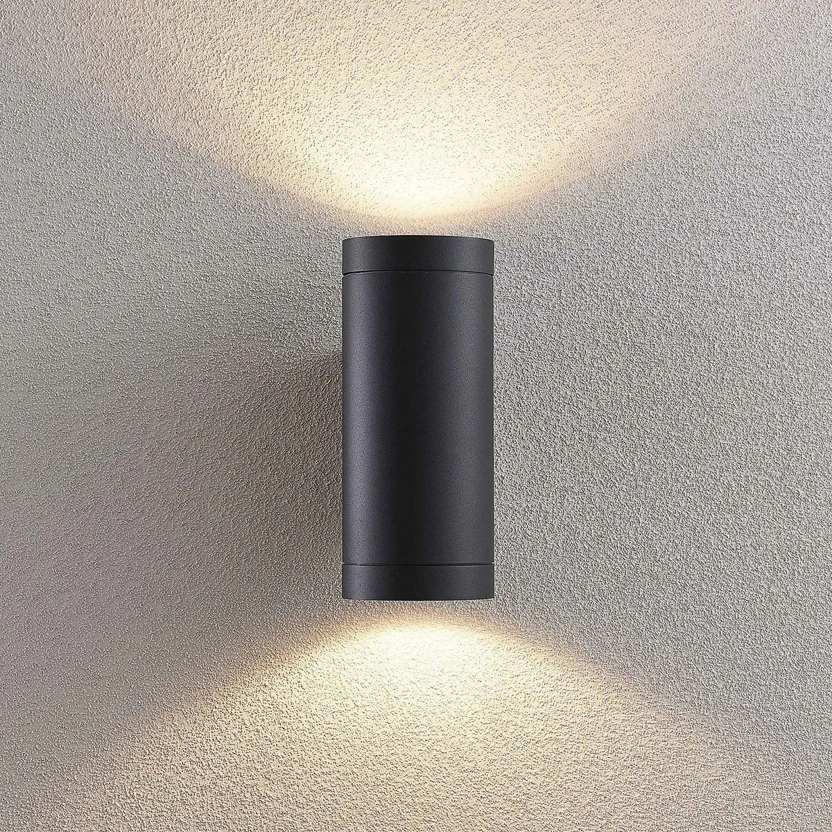 Tovi wall light lit at night showing the twin beam pattern on the wall