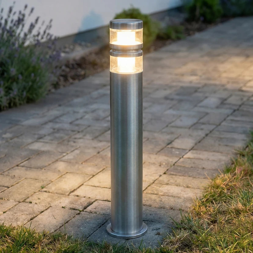 Vestro stainless steel path post light lit warm white beside a paved garden path